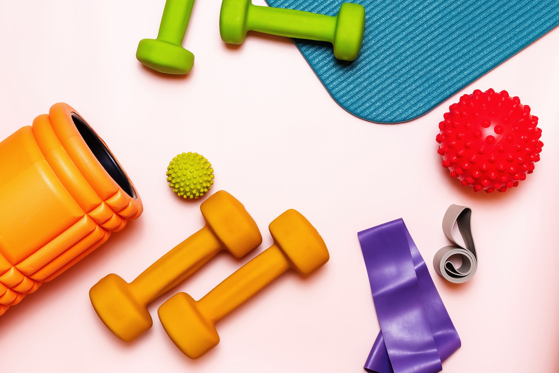 Collection of colorful fitness equipment, including dumbbells, bands, roller